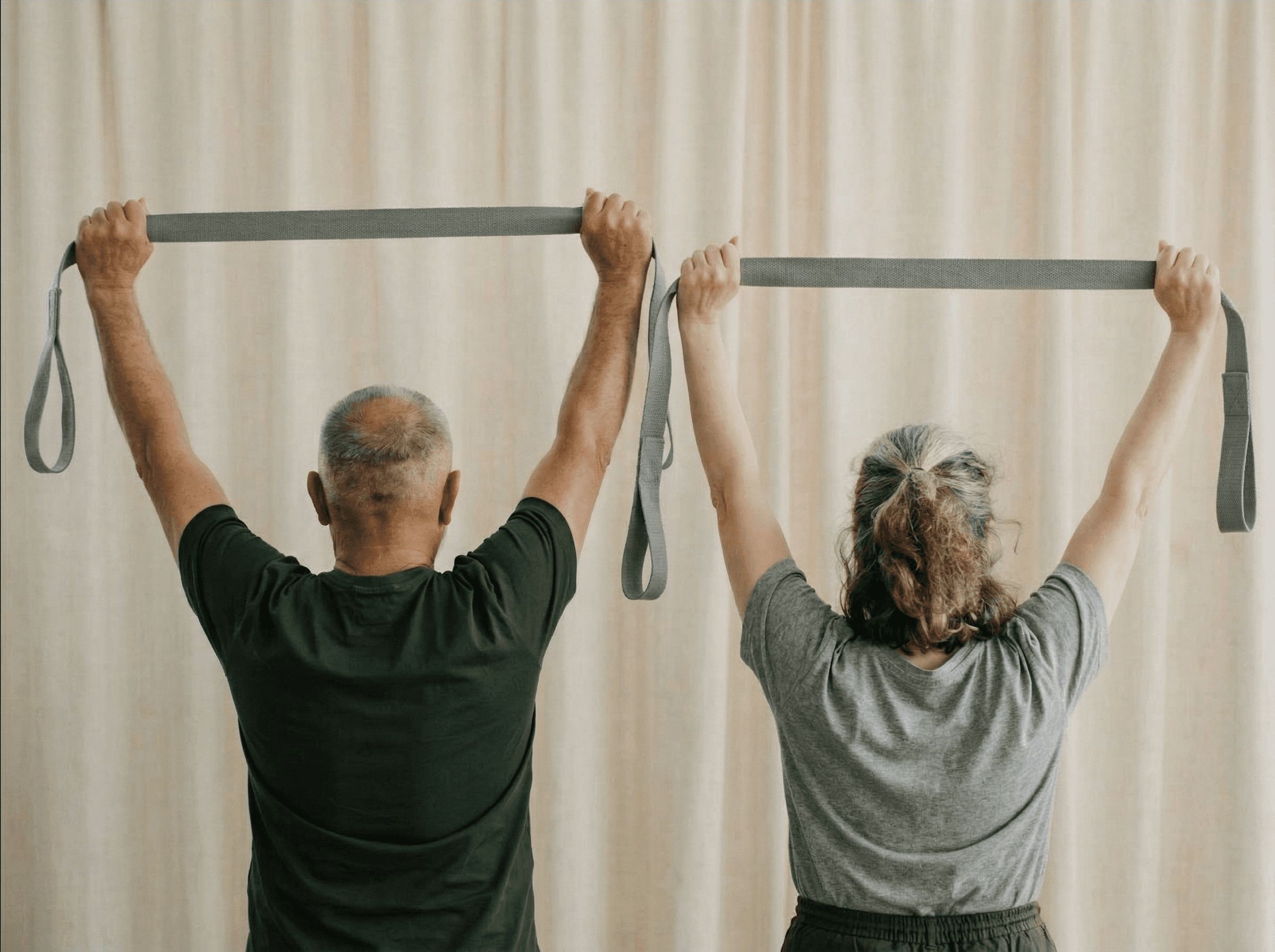 Zwei Erwachsene halten ein Yogaband über den Kopf, von hinten fotografiert